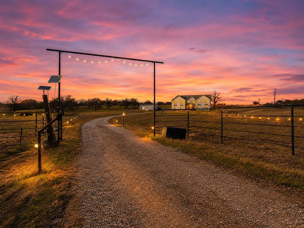 Gravel driveway with integrated path lighting and a decorative string-lit entryway arch