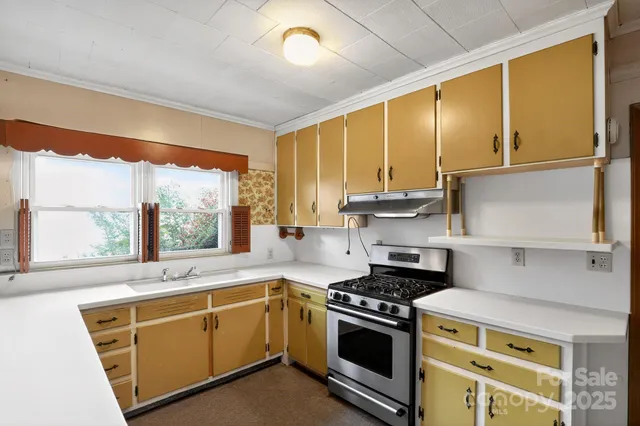 a kitchen with a sink a stove cabinets and a window