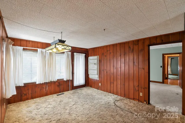 an empty room with windows and chandelier fan