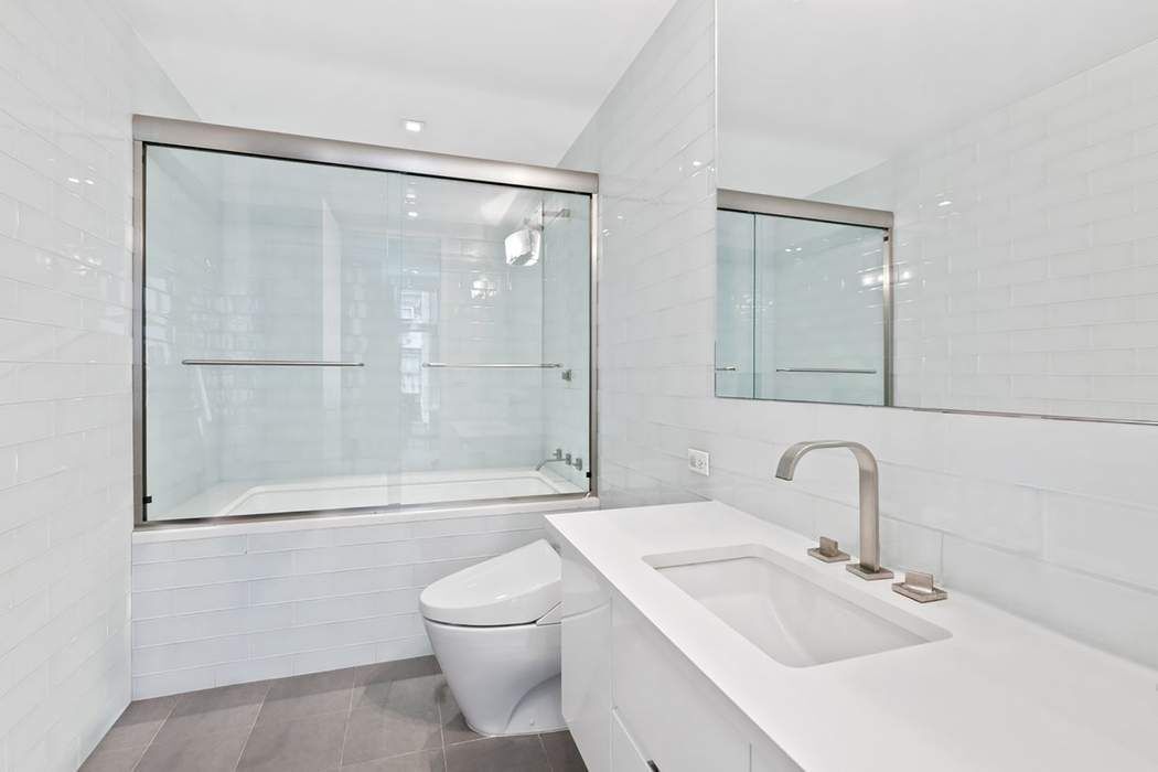 5 East 44th Street, Unit 12 Manhattan, NY 10017 - Photo 7 of 11 a bathroom with a sink mirror and a shower
