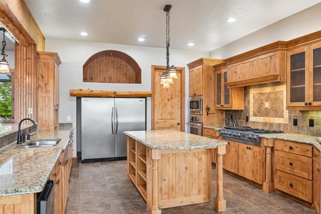 2085 Switzer Road Sanger, TX 76266 - Photo 9 of 39 Kitchen featuring extensive wood cabinetry, stainless steel appliances, granite countertops, and a central island