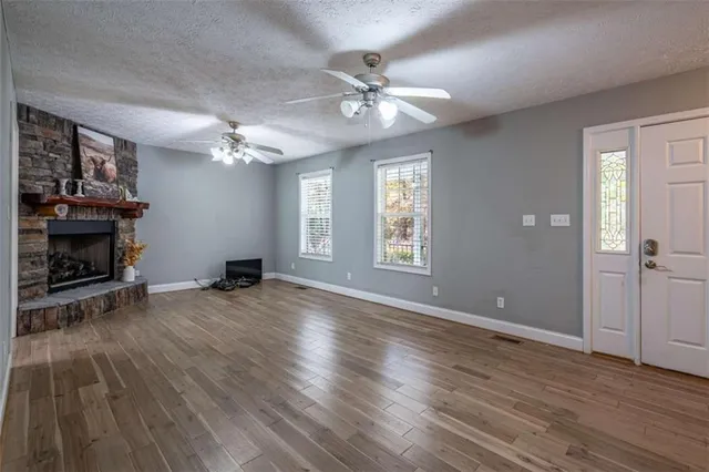 an empty room with wooden floor a ceiling fan and windows