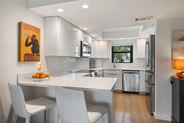 a kitchen with stainless steel appliances kitchen island granite countertop wooden floors and view living room