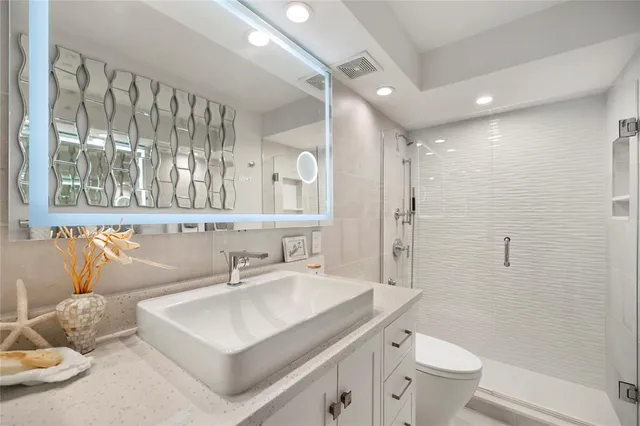 a bathroom with a double vanity sink toilet mirror and shower