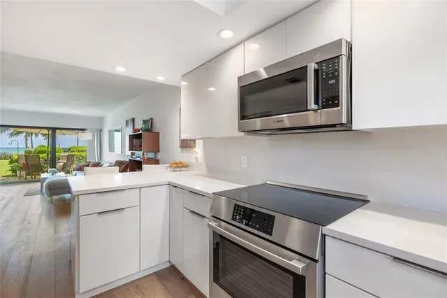 a kitchen with white cabinets appliances and a window