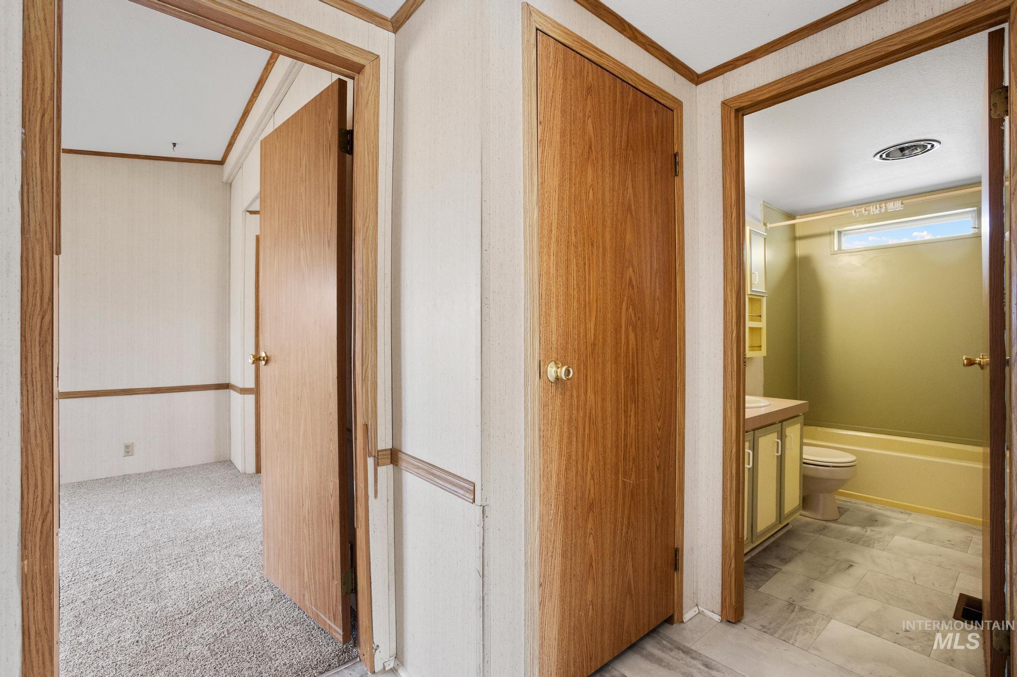 3680 South Mill Road Emmett, ID 83617 - Photo 24 of 38 Hallway featuring wood-finish doors and trim, leading to a carpeted room and a bathroom with tile flooring