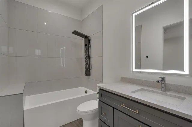 a bathroom with a granite countertop sink a toilet and bathtub