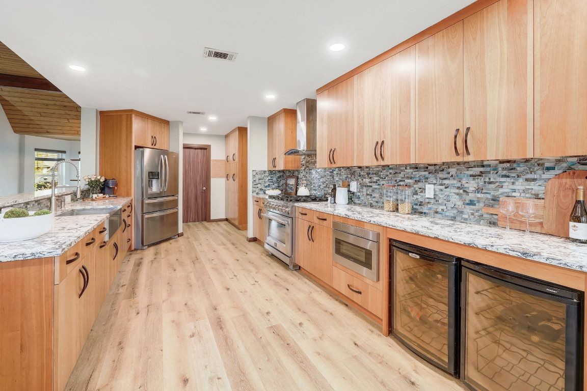 2307 Silverleaf Cove Round Rock, TX 78664 - Photo 11 of 31 a large kitchen with stainless steel appliances granite countertop a lot of counter space and wooden floors