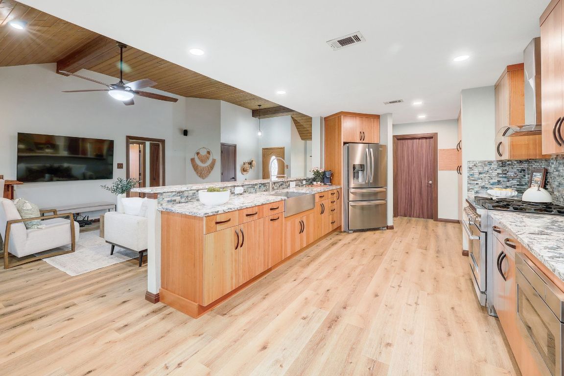 2307 Silverleaf Cove Round Rock, TX 78664 - Photo 12 of 31 a large kitchen with stainless steel appliances kitchen island granite countertop a large counter top and view of living room