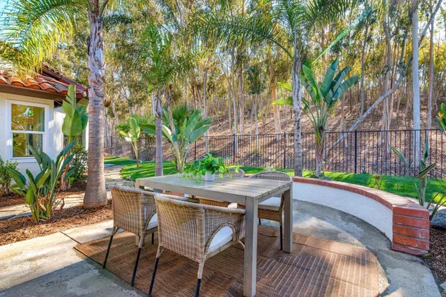 a patio with table and chairs and potted plants