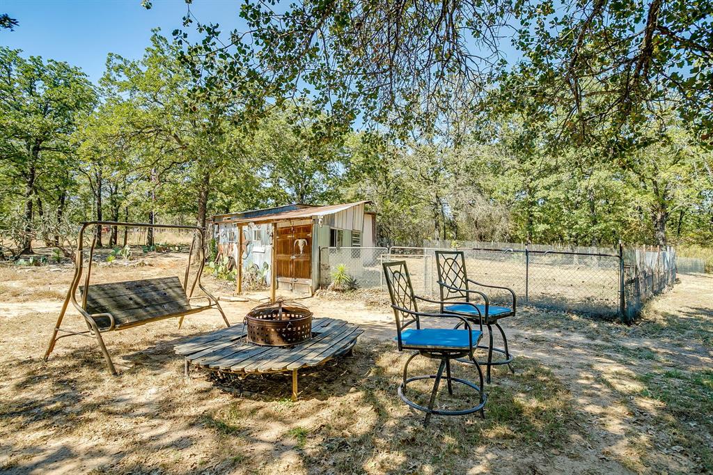 436 Luke Road Springtown, TX 76082 - Photo 32 of 39 View of yard with a fire pit, an outdoor structure, and view of wooded area