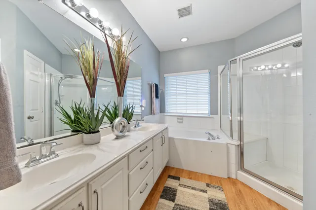 a bathroom with a double vanity sink a large mirror a bathtub and window