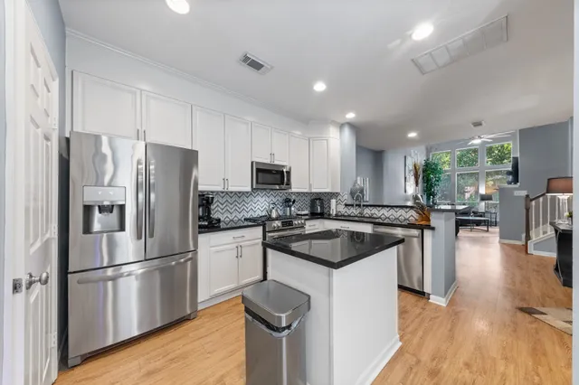 a kitchen with a sink stainless steel appliances and wooden floor