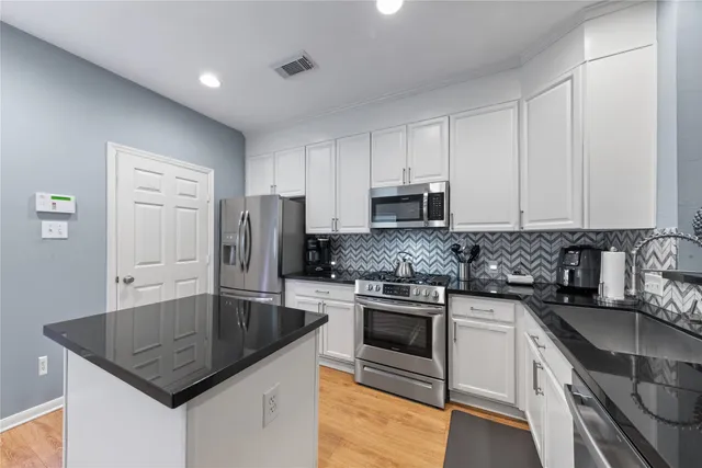 a kitchen with stainless steel appliances granite countertop a sink stove microwave and refrigerator