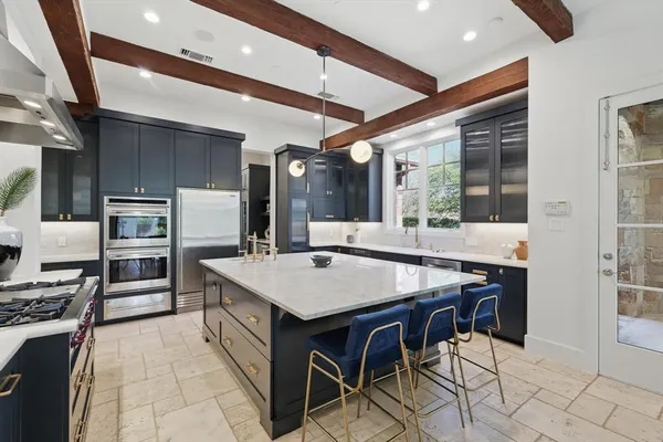 a kitchen with stainless steel appliances kitchen island granite countertop a table chairs in it and wooden floors