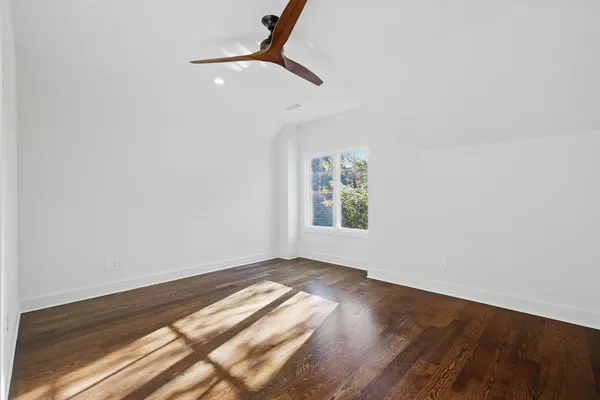 an empty room with wooden floor fan and windows