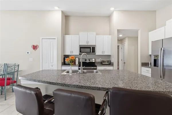 a kitchen with granite countertop kitchen island stainless steel appliances a sink stove refrigerator and a counter top space