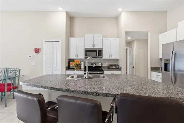 a kitchen with granite countertop kitchen island stainless steel appliances a sink stove refrigerator and a counter top space