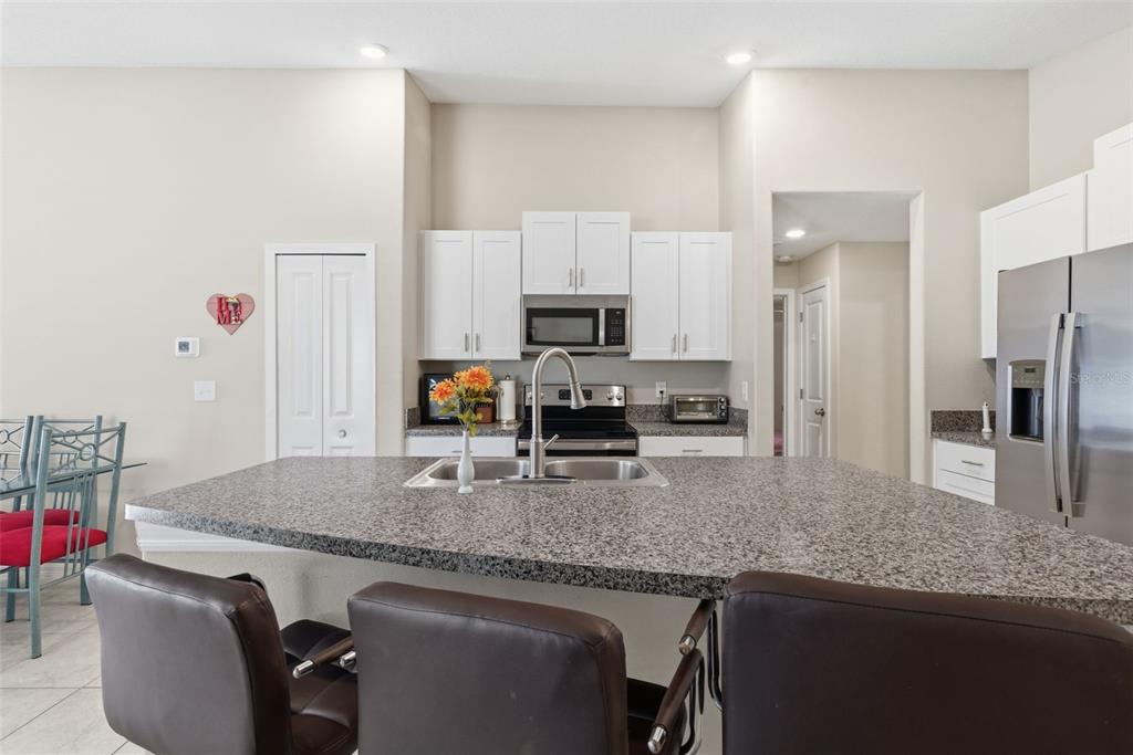 10239 Bright Crystal Avenue Riverview, FL 33578 - Photo 30 of 47 a kitchen with granite countertop kitchen island stainless steel appliances a sink stove refrigerator and a counter top space