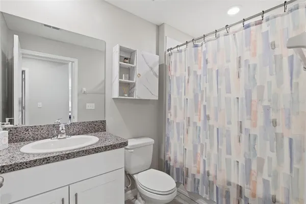 a bathroom with a granite countertop sink toilet and shower