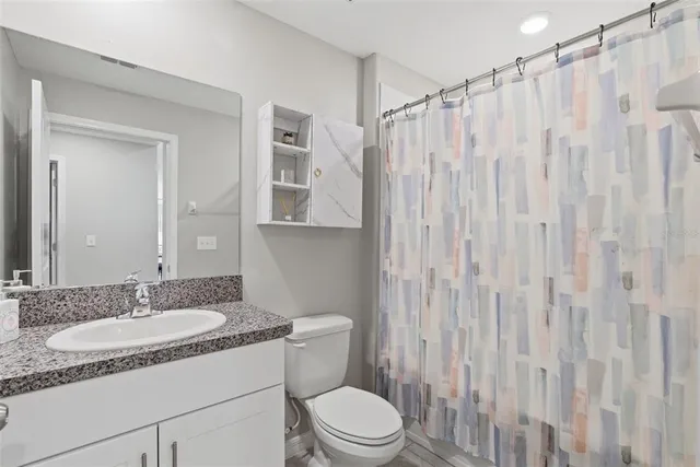 a bathroom with a granite countertop sink toilet and shower