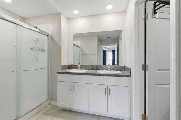 a bathroom with a granite countertop shower sink and mirror