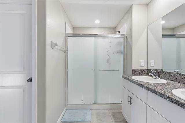 a bathroom with a granite countertop shower sink and mirror