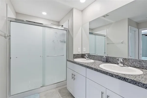 a bathroom with a granite countertop sink mirror and a shower