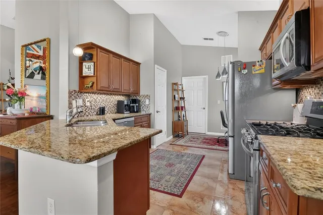 a kitchen with kitchen island granite countertop a sink stove and refrigerator