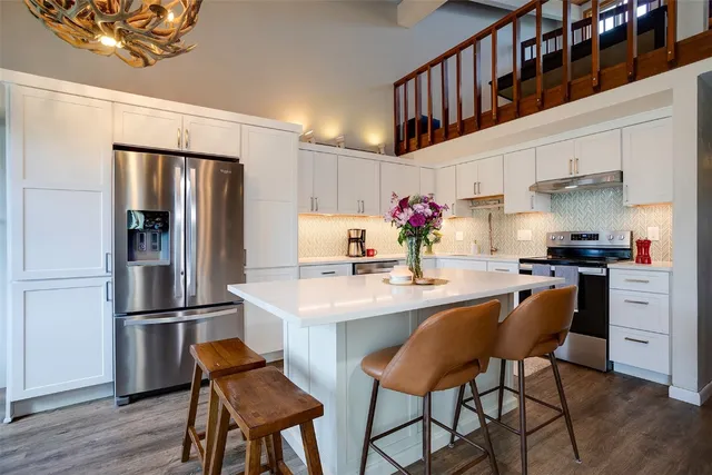 a kitchen with granite countertop a table chairs refrigerator and microwave