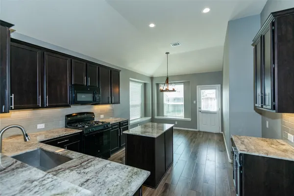 a kitchen with granite countertop stainless steel appliances a sink stove and refrigerator
