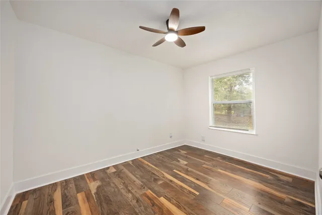 an empty room with a window and ceiling fan