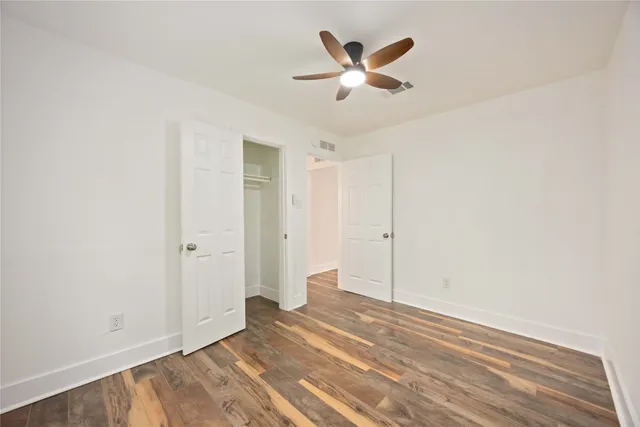 a view of a room with wooden floor and a ceiling fan