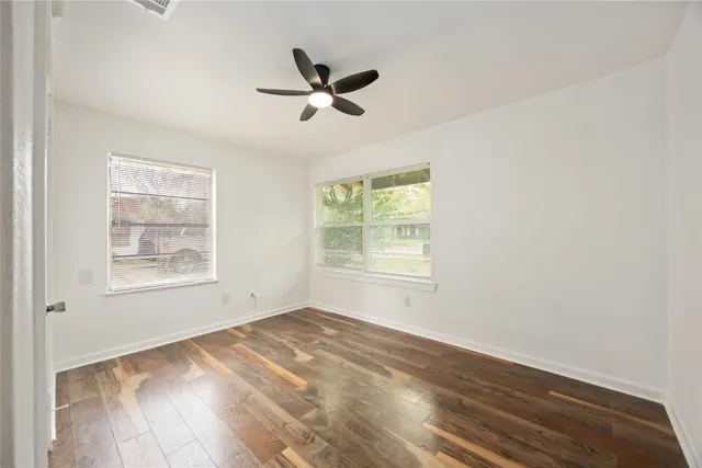 a view of empty room with wooden floor and fan