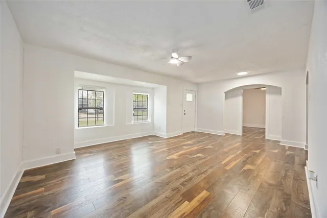 a view of an empty room with wooden floor and a window