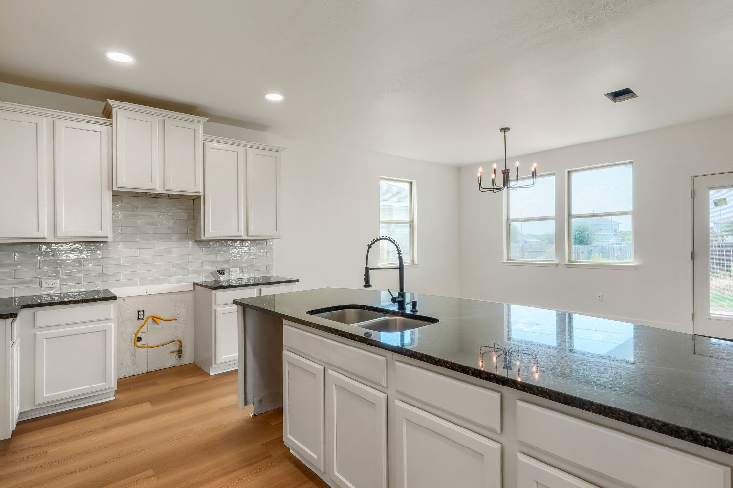 320 Triumph Road Buda, TX 78610 - Photo 8 of 22 Polished granite countertops anchor this airy, open kitchen featuring a central island and warm hardwood flooring.