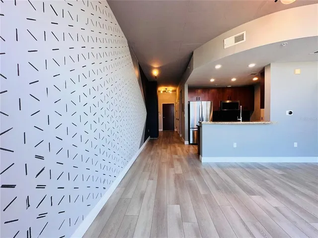 a view of a big room with wooden floor and windows