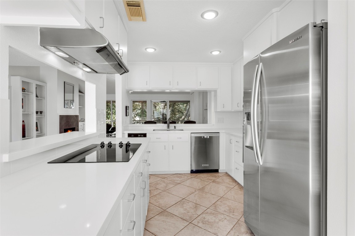 67 Harbor Lane Kemah, TX 77565 - Photo 10 of 47 a large white kitchen with cabinets a sink a counter top space stainless steel appliances and a chandelier