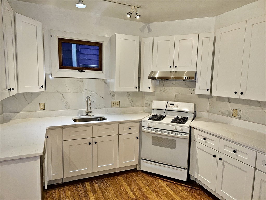 a kitchen with stainless steel appliances granite countertop a sink a stove and cabinets