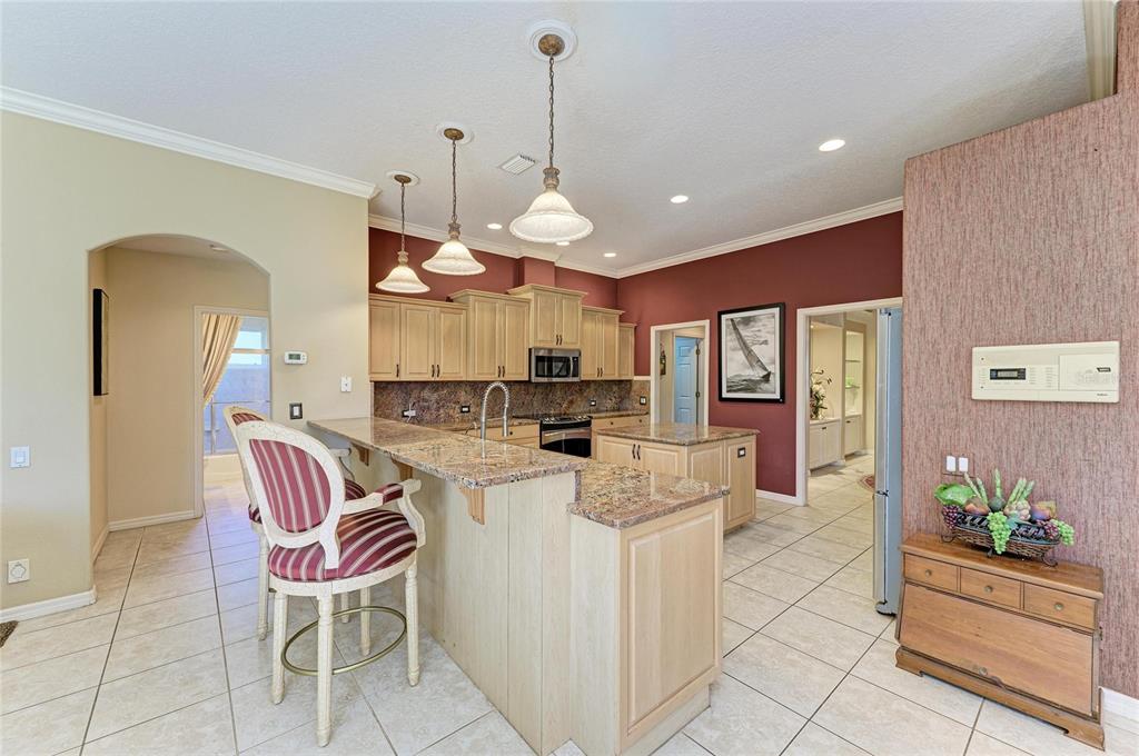 5060 Robinsong Road Sarasota, FL 34233 - Photo 15 of 42 a kitchen with stainless steel appliances kitchen island granite countertop a refrigerator a stove a sink a dining table and chairs with wooden floor