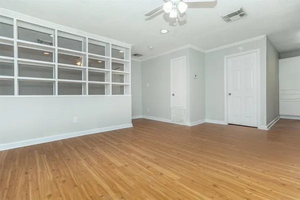a view of an empty room with wooden floor and a window