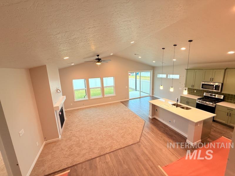 10400 Bellevue Ridge Street Nampa, ID 83687 - Photo 27 of 27 Kitchen featuring open floor plan, an island with sink, appliances with stainless steel finishes, decorative light fixtures, and a textured ceiling