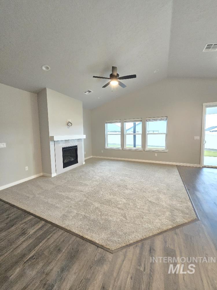 10400 Bellevue Ridge Street Nampa, ID 83687 - Photo 5 of 27 Unfurnished living room with a fireplace, lofted ceiling, a textured ceiling, ceiling fan, and dark wood-style flooring