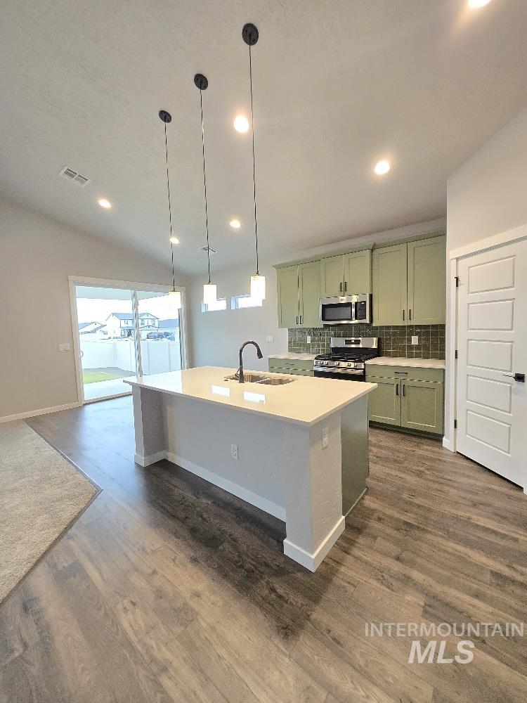 10400 Bellevue Ridge Street Nampa, ID 83687 - Photo 8 of 27 Kitchen featuring green cabinetry, pendant lighting, appliances with stainless steel finishes, an island with sink, and dark wood-style flooring