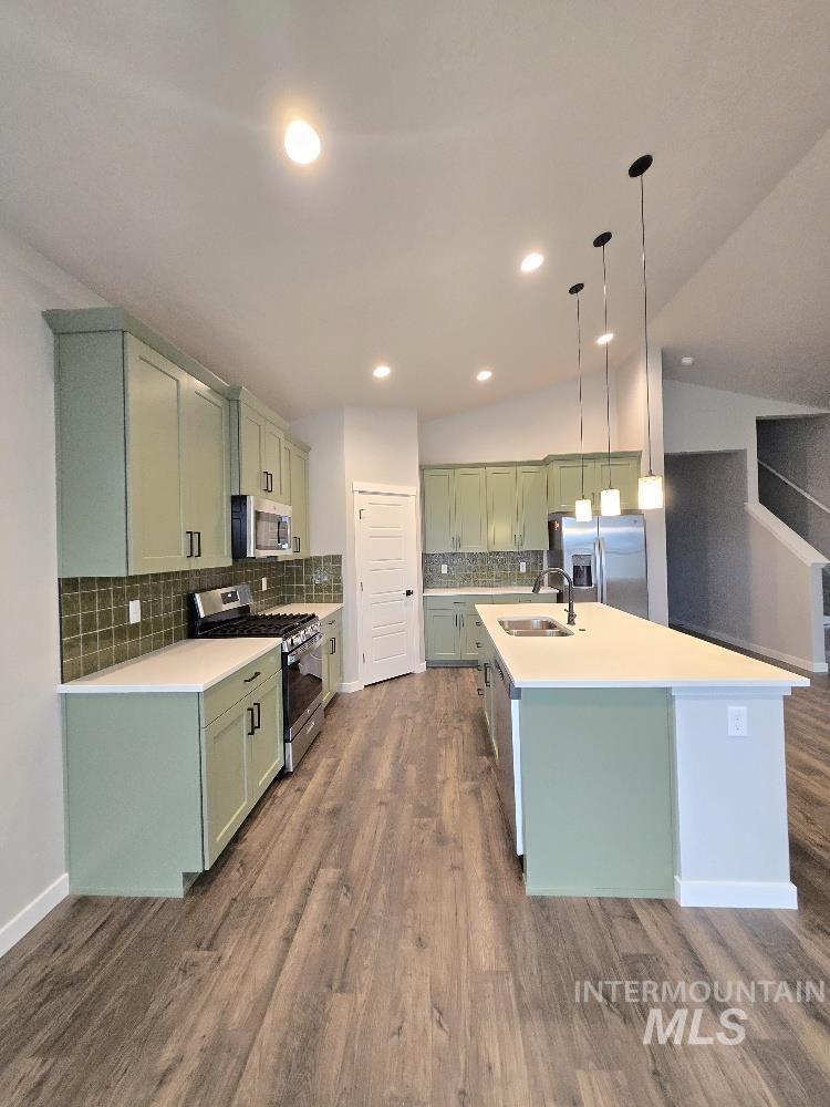 10400 Bellevue Ridge Street Nampa, ID 83687 - Photo 9 of 27 Kitchen featuring green cabinetry, appliances with stainless steel finishes, a center island with sink, decorative backsplash, and vaulted ceiling