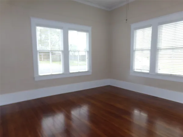 an empty room with wooden floor closet and windows