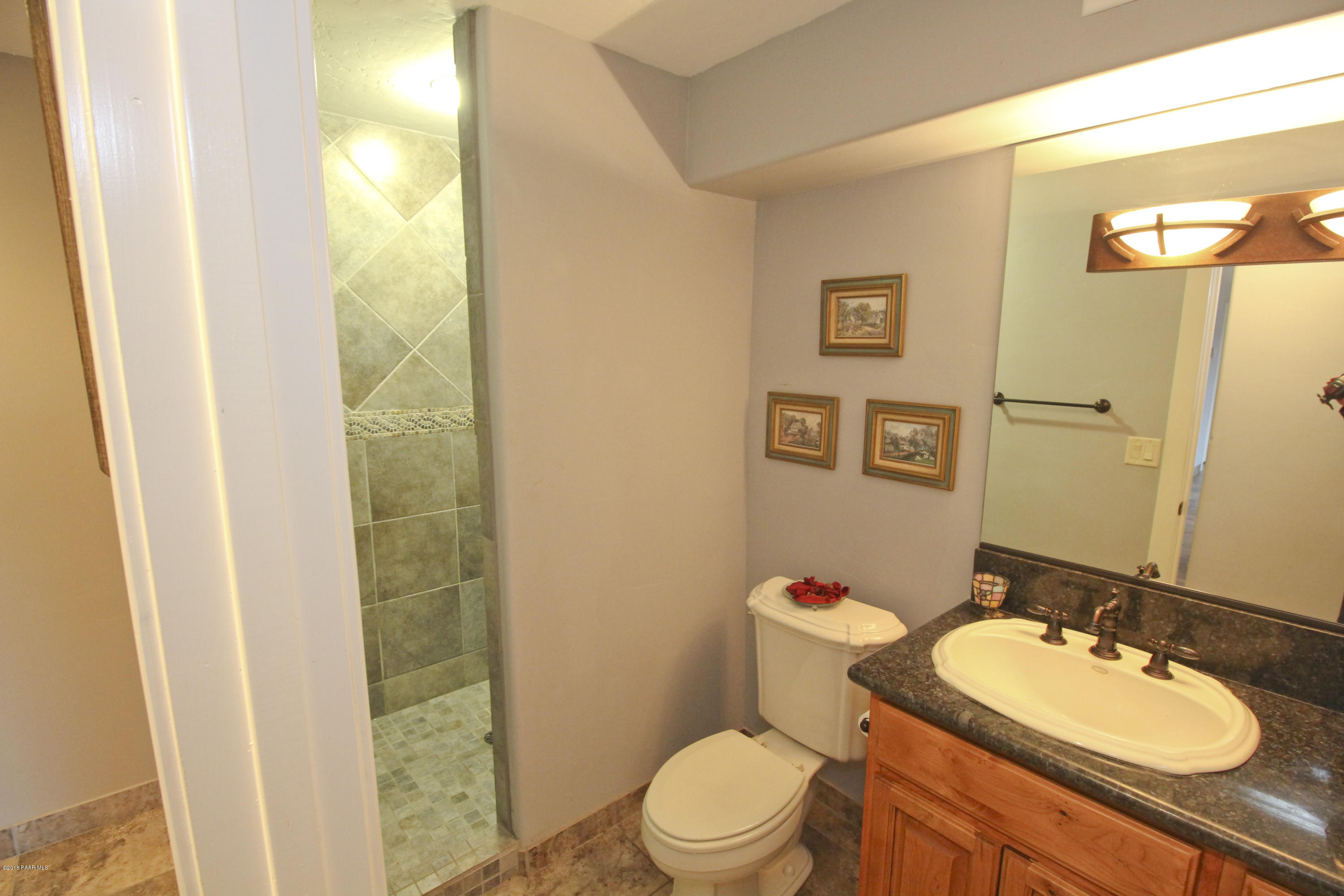 4800 West Mint Creek Road Prescott, AZ 86305 - Photo 26 of 62 a bathroom with a granite countertop toilet sink and mirror