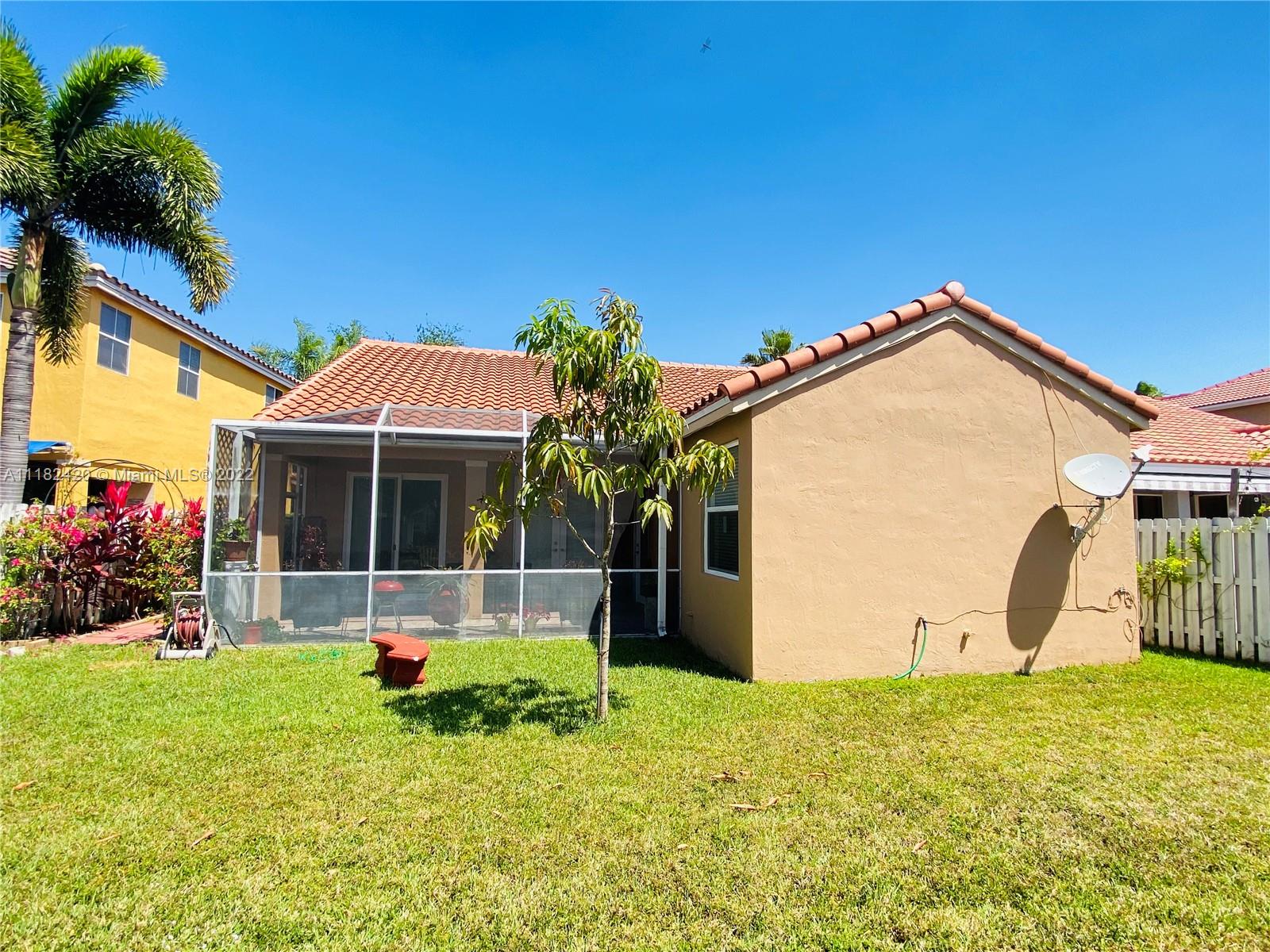 944 Falling Water Road Weston, FL 33326 - Photo 30 of 37 a backyard of a house with table and chairs