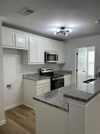 a kitchen with granite countertop cabinets stainless steel appliances and a counter space