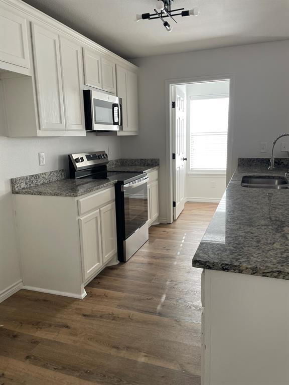 212 Mineral Wells Street Terrell, TX 75160 - Photo 5 of 16 a kitchen with granite countertop a stove top oven a sink dishwasher and white cabinets with wooden floor